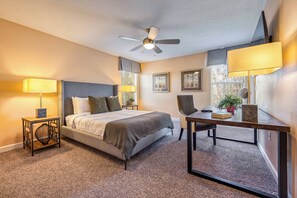 A hotel room with a bed, bedside table, chair, desk, ceiling fan, and window with blinds. - Cg9025 - 5BR House With Pool Near Disney (Davenport)