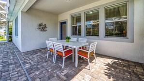 A patio with a white table and chairs, a potted plant, and a blue door. - Cg9025 - 5BR House With Pool Near Disney (Davenport)