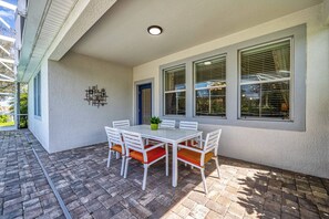Eine Terrasse mit einem weißen Tisch und Stühlen, einem Blumentopf und einer blauen Tür.