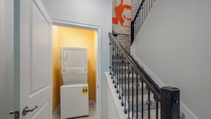 A laundry room with stacked washers and dryers, a staircase with a metal railing, and a yellow wall. - Cg9025 - 5BR House With Pool Near Disney (Davenport)
