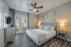 A bedroom with a bed, ceiling fan, artwork, bedside lamps, and a view through a door. - Th20 - 3BR House With Resort Access Near Parks (Orlando)