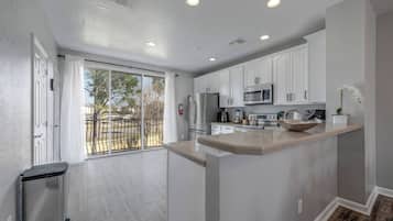 A modern kitchen with white cabinets, a central island, and a sliding glass door leading to a balcony.