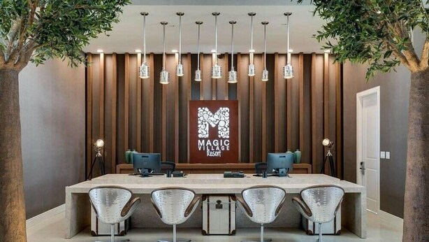 A modern reception area with a long counter, four chairs, and a sign reading "MAGIC VILLAGE Resort". - Mvy7632 - 4BR House Near Disney (Kissimmee)