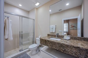 A modern bathroom with a glass shower enclosure, a toilet, a sink, and a large mirror. - Mvy7632 - 4BR House Near Disney (Kissimmee)