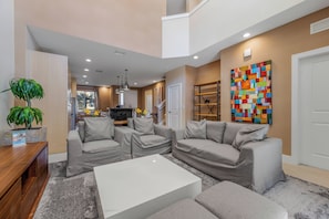 A modern living room with grey sofas, a white coffee table, and a colorful abstract painting on the wall. - Mvy7632 - 4BR House Near Disney (Kissimmee)