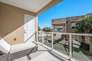 A balcony with a glass railing, a white door, and a wicker sofa. - Mvy7632 - 4BR House Near Disney (Kissimmee)