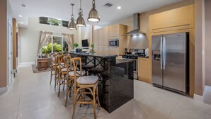 A modern kitchen with a central island, bar stools, stainless steel appliances, and pendant lighting. - Mvy7632 - 4BR House Near Disney (Kissimmee)
