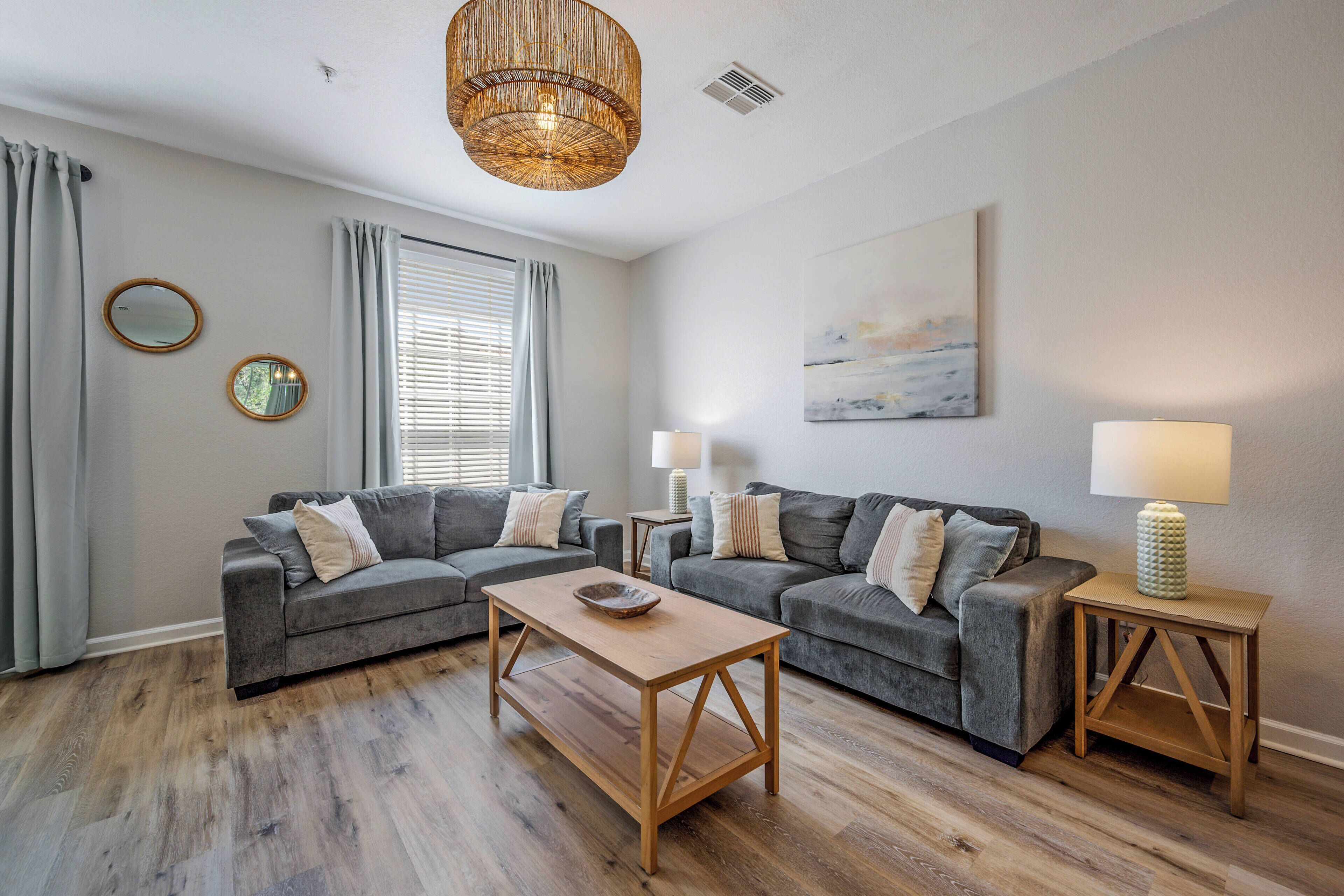 A living room with two grey sofas, a wooden coffee table, and two side tables with lamps.