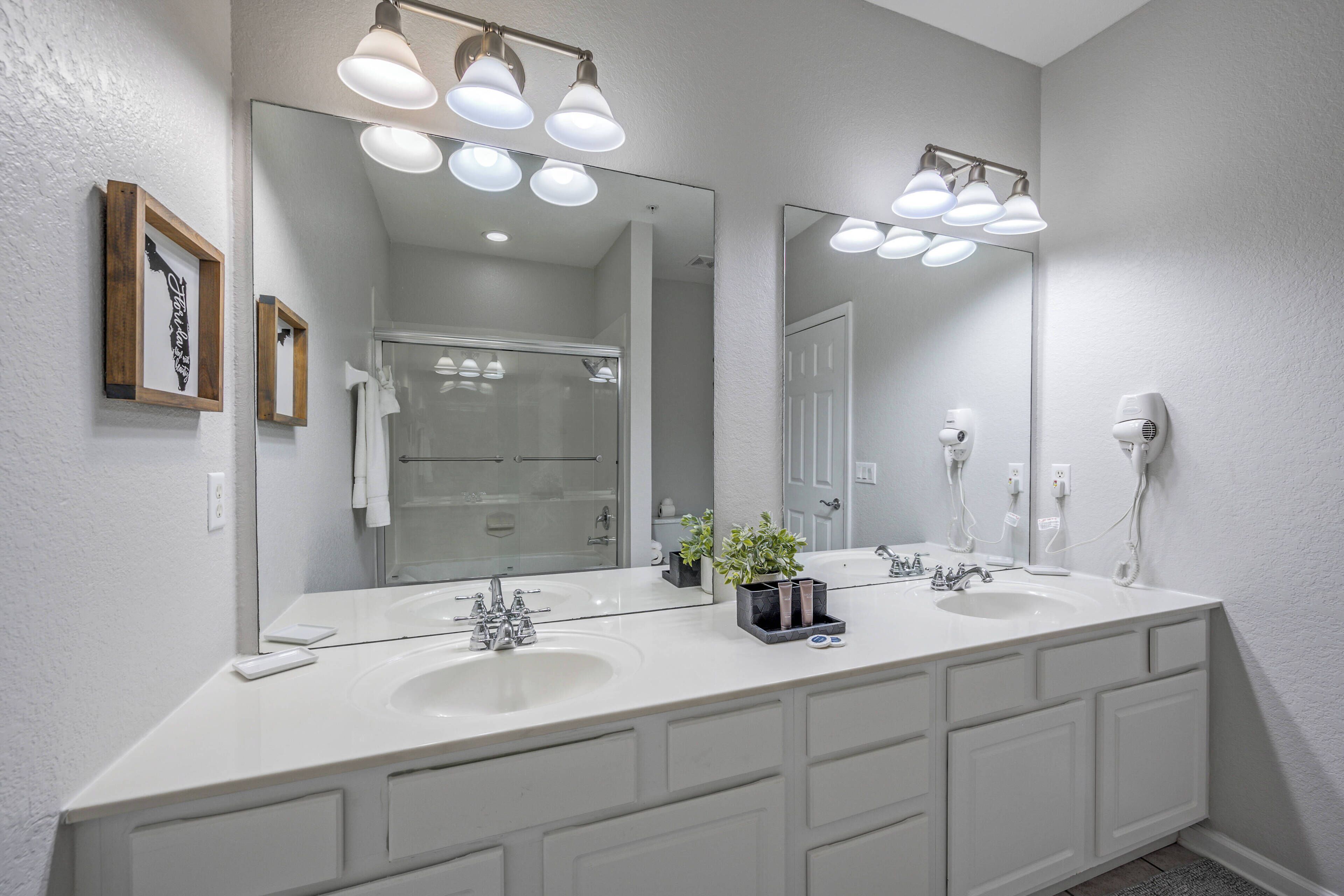A modern bathroom with two sinks, a large mirror, and overhead lighting.