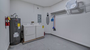 Un cuarto de lavado con calentador de agua, lavadora y tendedero.