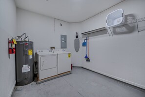 Une buanderie équipée d’un chauffe-eau, d’une machine à laver et d’un étendoir.