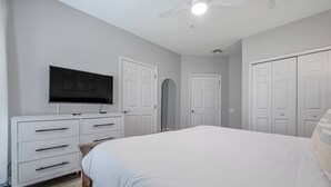 Un dormitorio con cama, cómoda, televisor y armario.