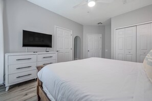 Une chambre à coucher avec un lit, une commode, un téléviseur et une armoire.