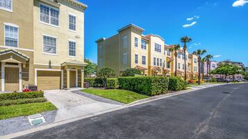 A row of townhouses with a garage, a well-maintained lawn, and a clear blue sky.