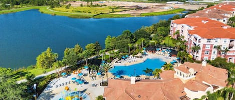 A resort with a large swimming pool, a water park, and a view of a lake.