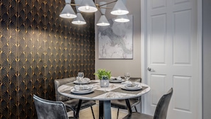 A dining area with a round table, black chairs, and a chandelier. There is a plant on the table and a door in the background. - Vc6-105 - 3BR Condo Resort Access Near Disney (Orlando)