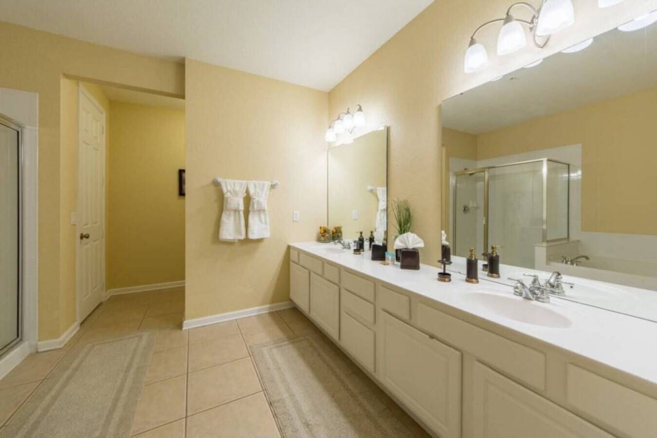 A modern bathroom with a large vanity, a walk-in shower, and a mirror with lights.