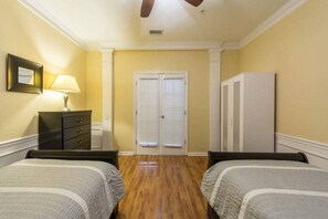 A bedroom with two beds, a dresser, a lamp, a wardrobe, and a door with blinds. - Vc6-105 - 3BR Condo Resort Access Near Disney (Orlando)