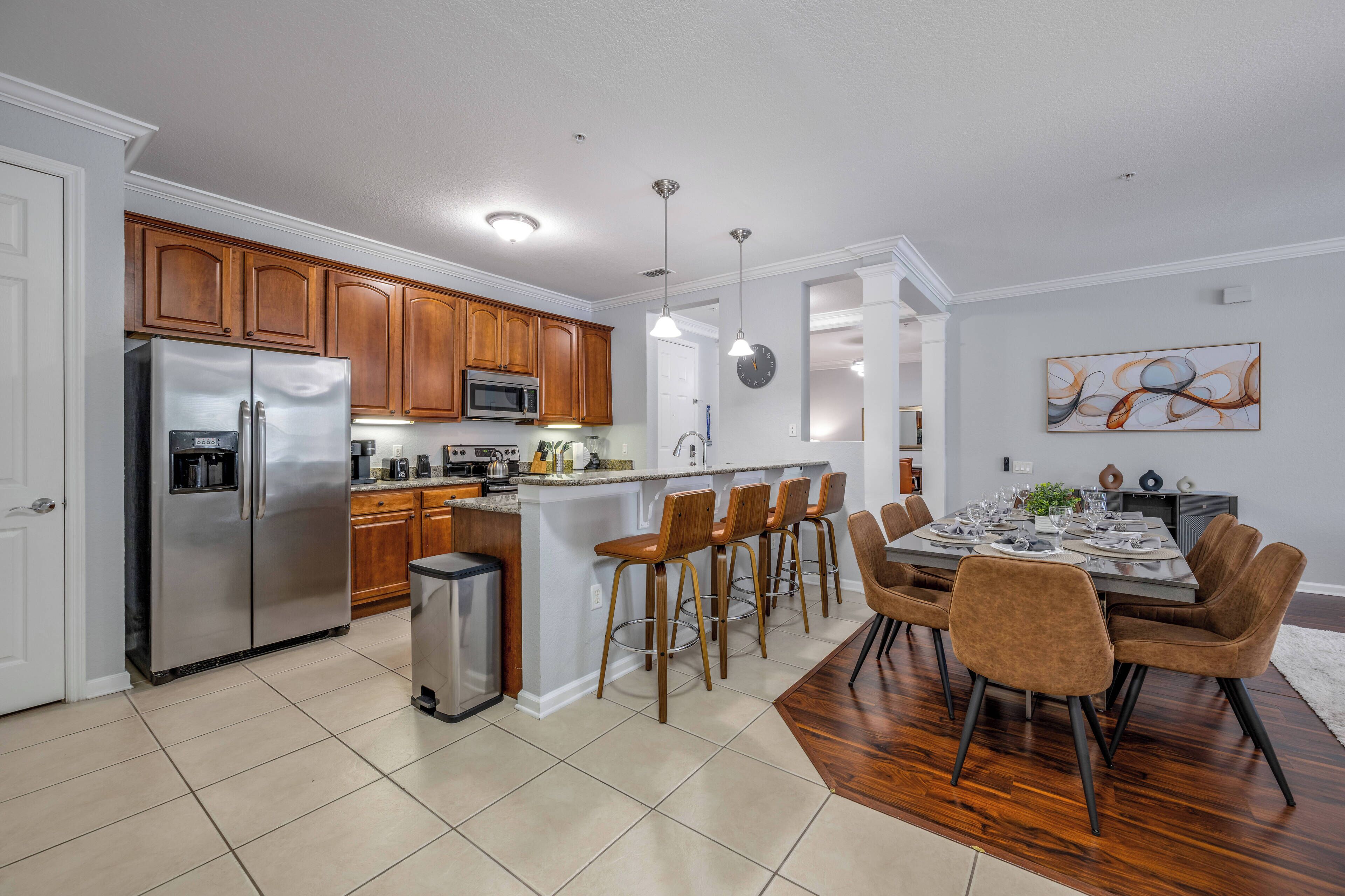 Een moderne keuken met houten kastjes, roestvrijstalen apparatuur en een eethoek met een houten tafel en stoelen.