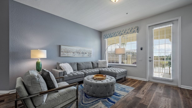 A living room with a sectional sofa, ottoman, and a lamp. - Vc12-206 - 3BR Condo Lake View Near Disney (Orlando)