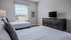 A bedroom with two beds, a dresser, a television, and a window with blinds. - Vc12-206 - 3BR Condo Lake View Near Disney (Orlando)