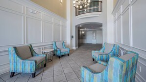 A spacious lobby with a high ceiling, a chandelier, and a balcony with a railing. - Vc12-206 - 3BR Condo Lake View Near Disney (Orlando)