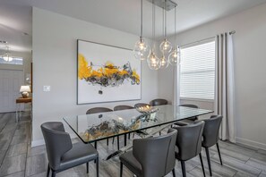 Ein moderner Essbereich mit einem Tisch mit Glasplatte, sechs Stühlen und einem zeitgenössischen abstrakten Gemälde an der Wand.