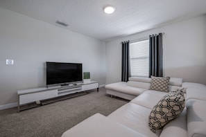Ein modernes Wohnzimmer mit Flachbildfernseher, weißem Sofa und minimalistischem Design.