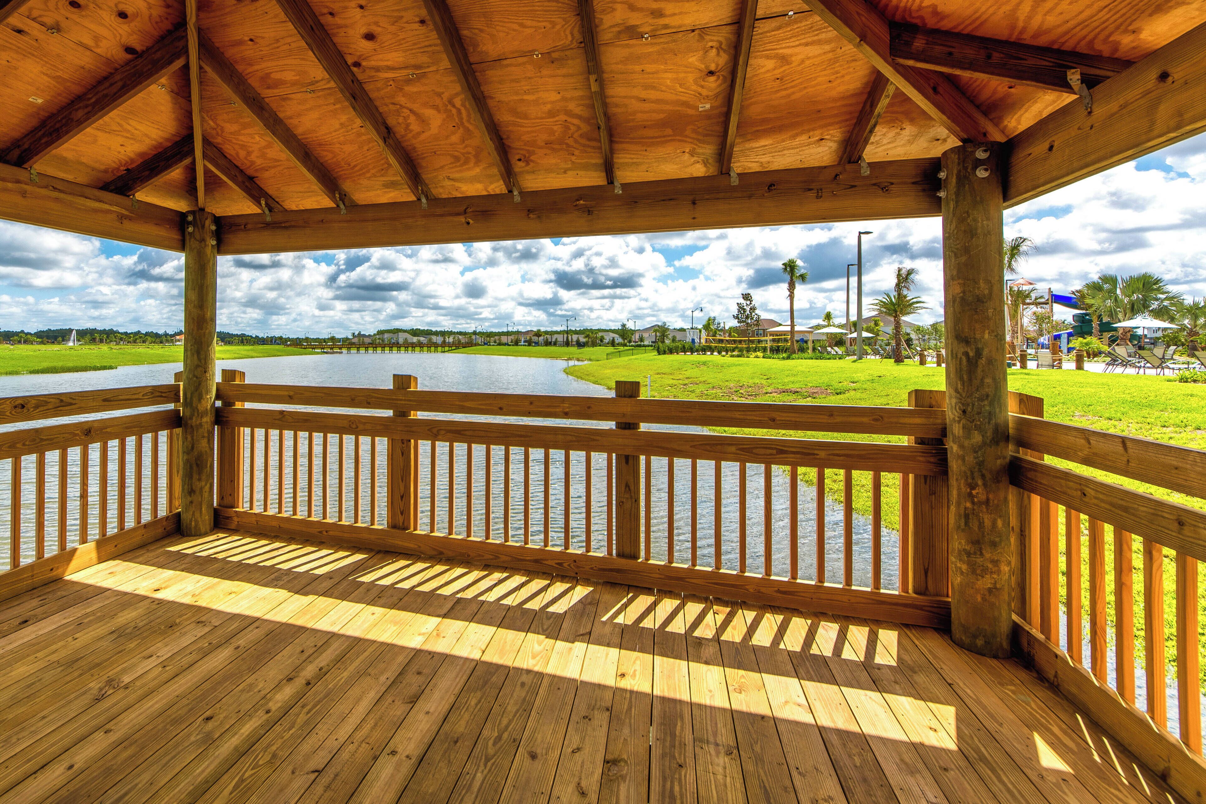 Una terraza de madera con vistas a un lago y zonas verdes.