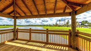 Una terraza de madera con vistas a un lago y zonas verdes.