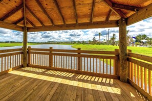 A wooden deck with a view of a lake and grassy areas. - Sl4721-307 - 2BR Apartment Near Disney Attractions (Kissimmee)