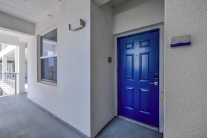 Um corredor com uma porta azul, uma janela e uma placa com o número da porta.