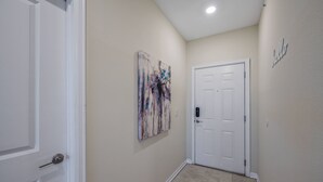 Un pasillo con una puerta blanca, paredes color beige y una obra de arte con textura en la pared.