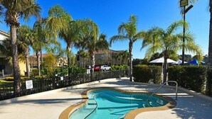A swimming pool with a unique shape, surrounded by palm trees and a fence. - Ow2819 - 2BR Apartment With Balcony Near Disney (Kissimmee)