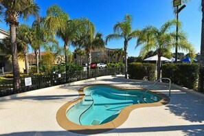 A swimming pool with a unique shape, surrounded by palm trees and a fence. - Ow2819 - 2BR Apartment With Balcony Near Disney (Kissimmee)