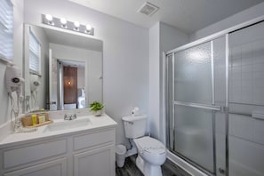 A bathroom with a white sink, a mirror with lights, a toilet, and a shower area. - Ei8555 - 3BR House Near Disney (Kissimmee)