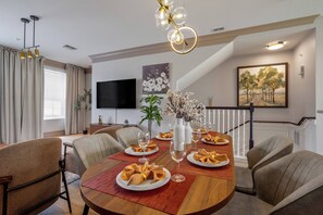A dining room with a wooden table set for six, surrounded by upholstered chairs. There are decorative vases with flowers on the table, and a painting on the wall above. - Th14 - 3BR House With Pool Access Near Disney (Orlando)