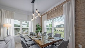 Een eethoek met een houten tafel voor zes personen, omringd door grijze stoelen, met een potplant en een lamp op de tafel.