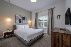 Ein modernes Hotelzimmer mit einem großen Bett, Nachttischen, einem Schreibtisch und einem Fernseher.
