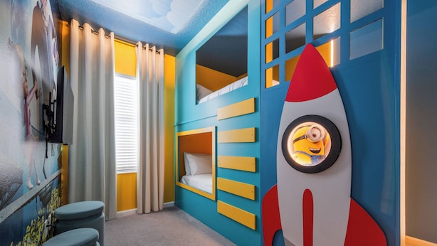 Een kinderkamer met een stapelbed, een raketdecoratie aan de muur en een raam met gordijnen.