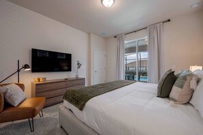 A bedroom with a large bed, a TV mounted on the wall, a dresser, and a window with a view of a balcony. - Wi3277 - 5BR House Near Disney With Private Pool (Davenport)