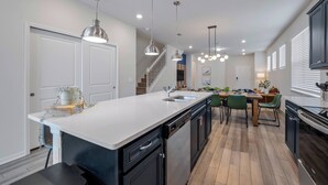 A modern kitchen with a central island, black cabinetry, and pendant lighting. - Wi3277 - 5BR House Near Disney With Private Pool (Davenport)