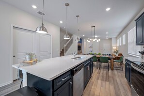 A modern kitchen with a central island, black cabinetry, and pendant lighting. - Wi3277 - 5BR House Near Disney With Private Pool (Davenport)