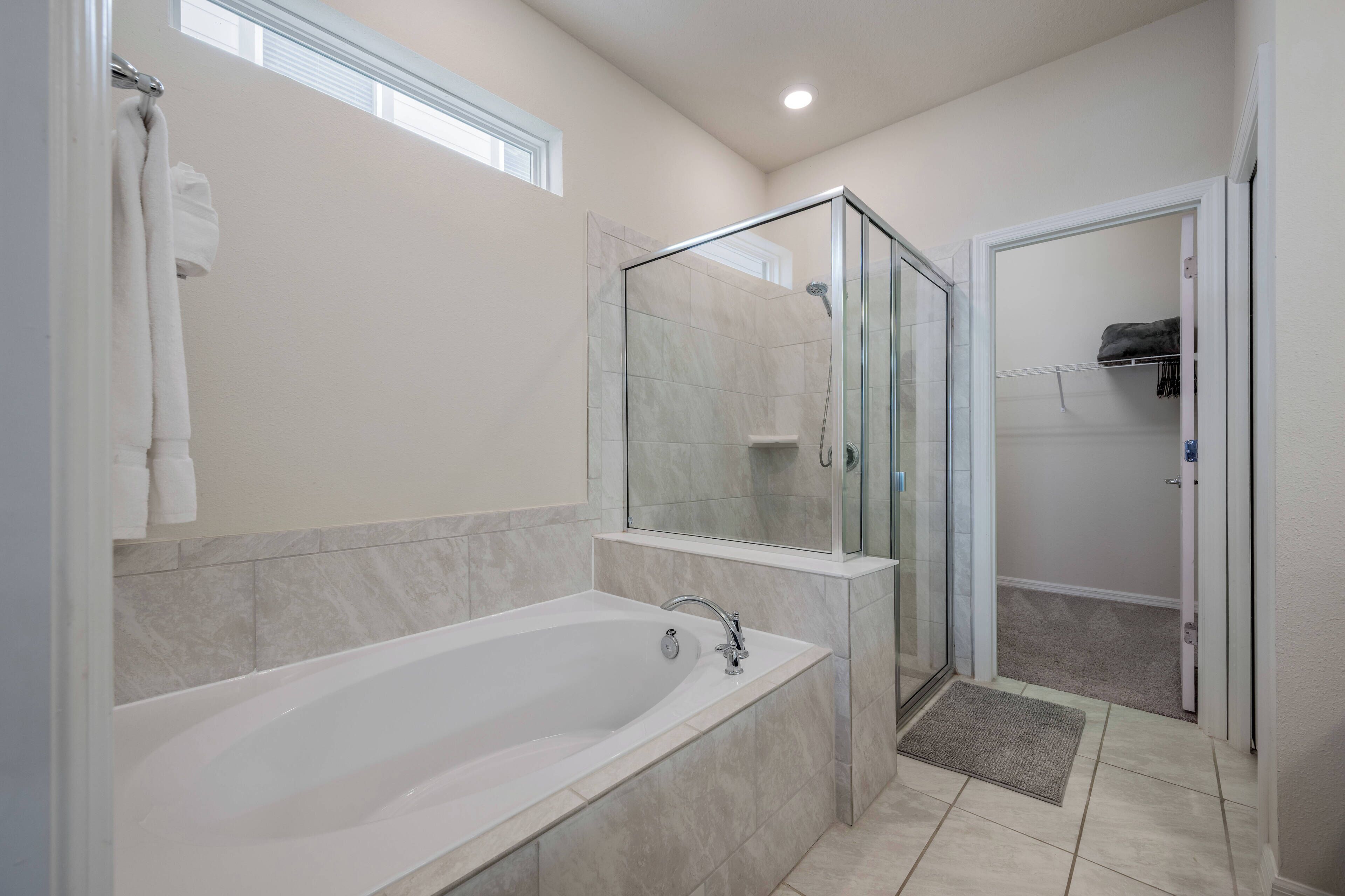 A modern bathroom with a freestanding bathtub, a glass-enclosed shower, and a walk-in closet with a door.