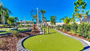 A well-maintained golf course with a putting green, surrounded by landscaped areas and palm trees. - Wi3277 - 5BR House Near Disney With Private Pool (Davenport)
