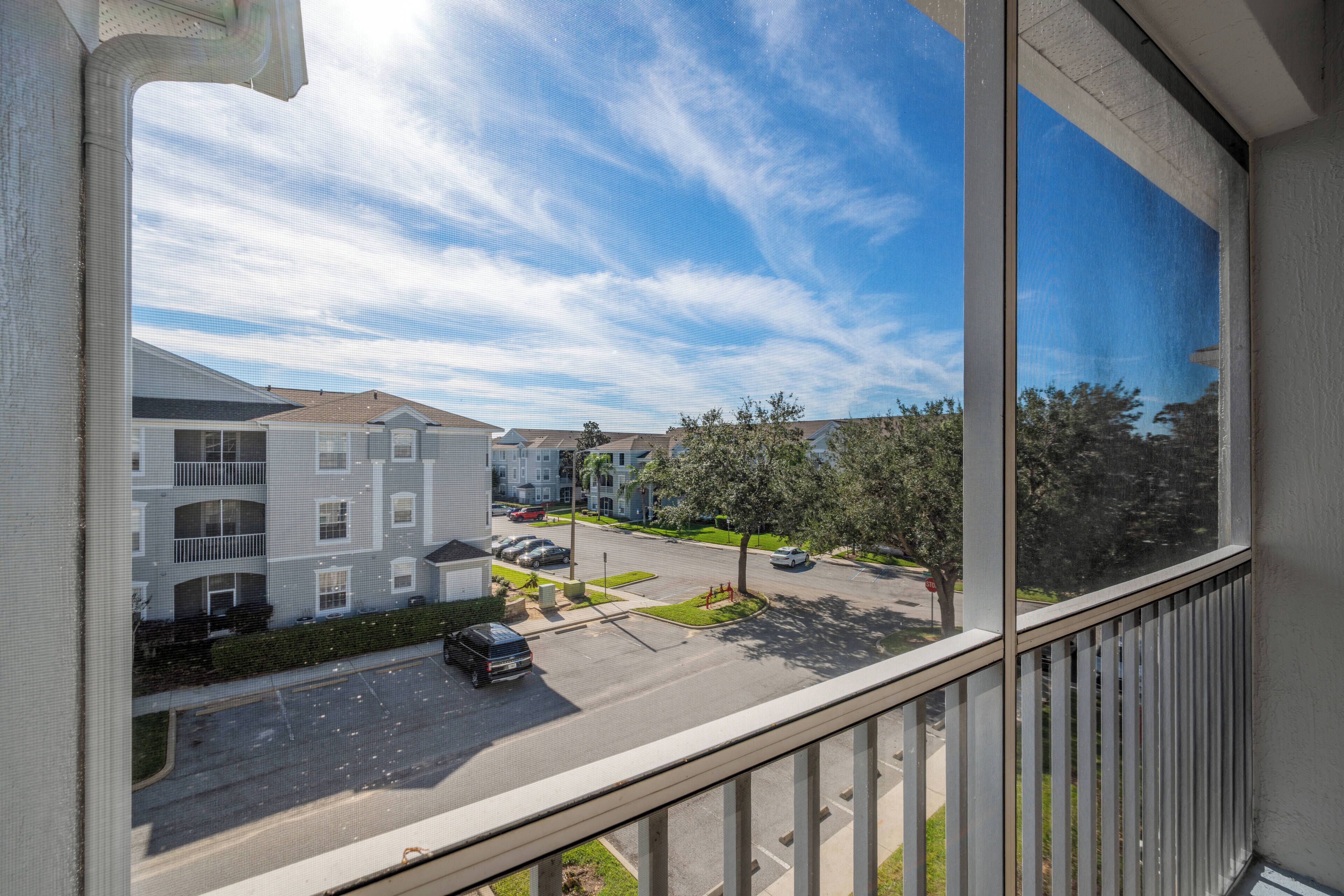 A residential area with multi-story buildings, a parking lot, and a clear blue sky.