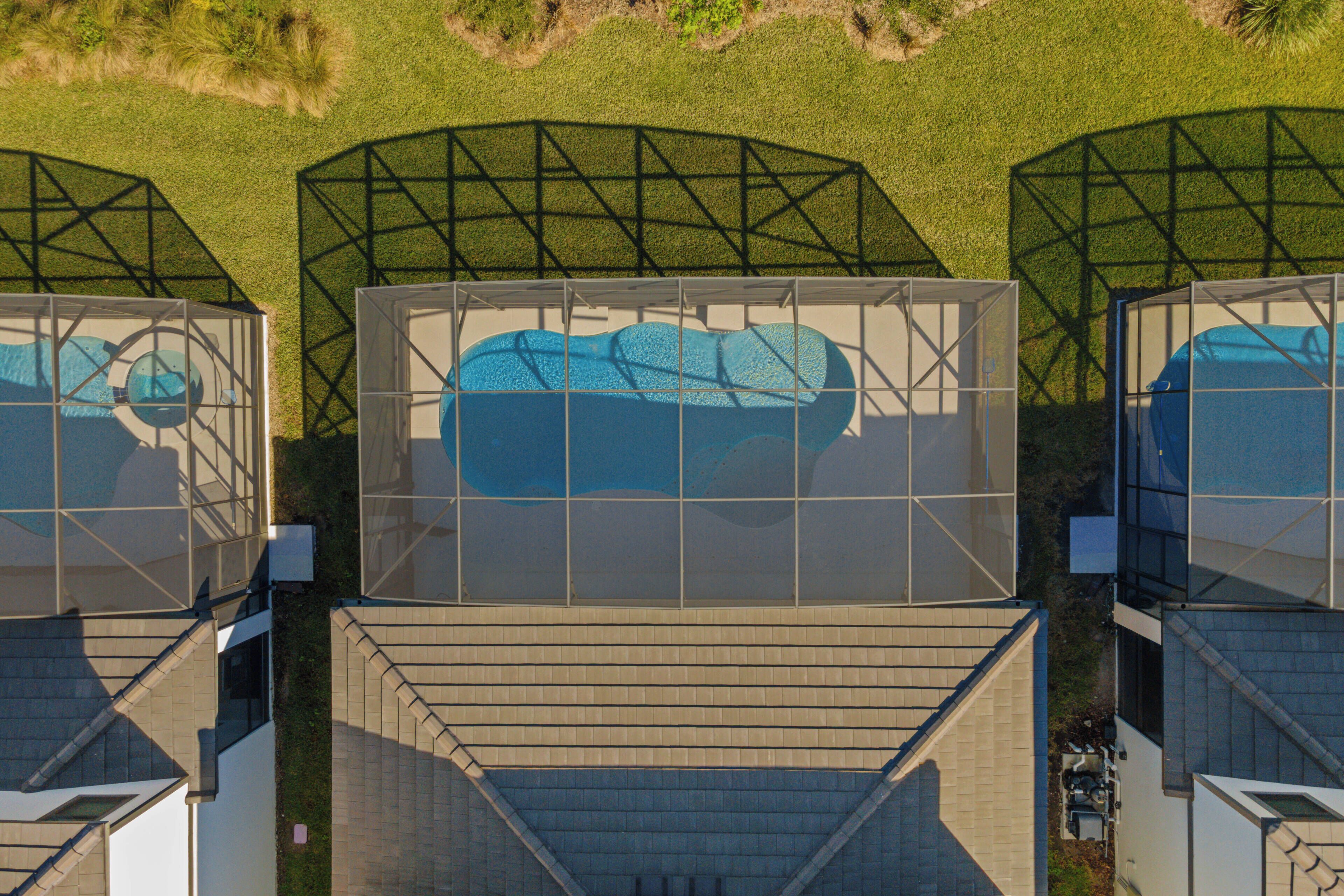 A rooftop with a swimming pool, surrounded by a metal framework and a grassy area.