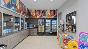 En lys butik med hylder fyldt med diverse produkter, kølediske og farverige oppustelige ringe.