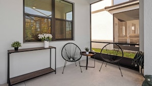 En balkon med to sorte stole, et lille bord og en plantekasse.
