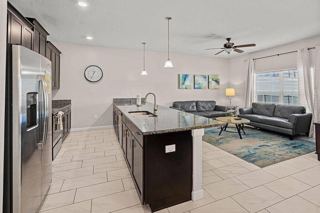 A modern kitchen with a central island, a dining area with a sofa, and a living room with a couch.